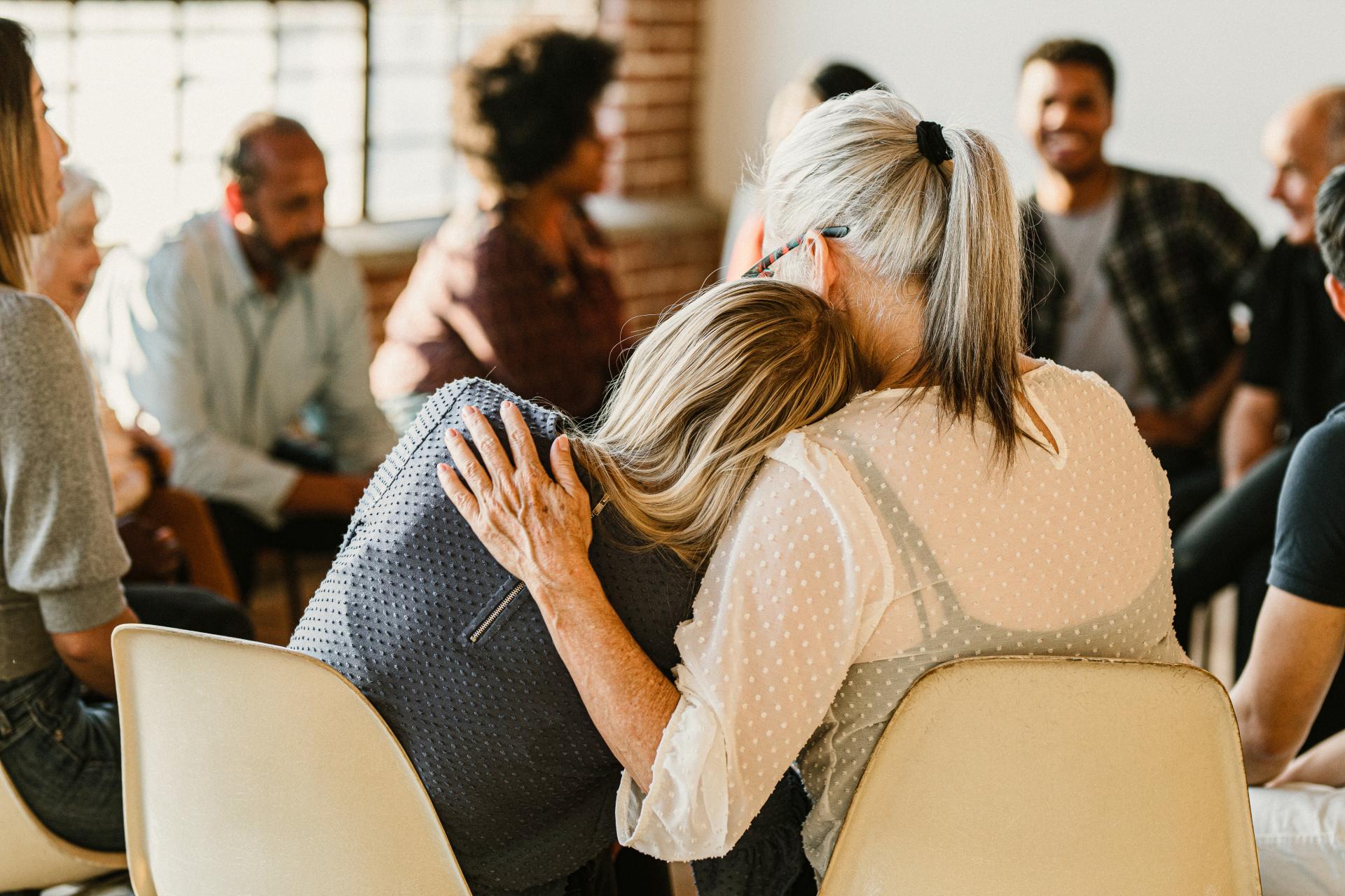 Circle of people talking, two in foreground comforting each other